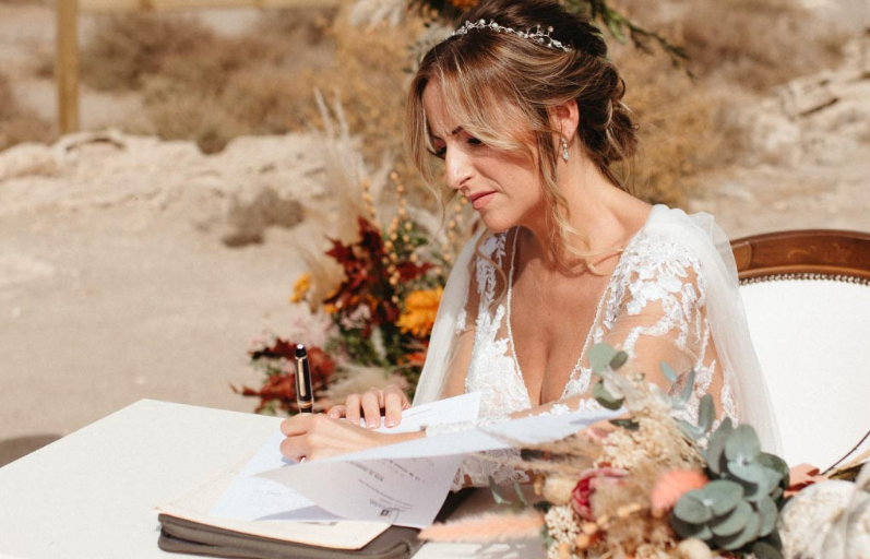 Novia firmando los documentos de su boda durante una ceremonia al aire libre organizada por Eventos SJ en Almería.